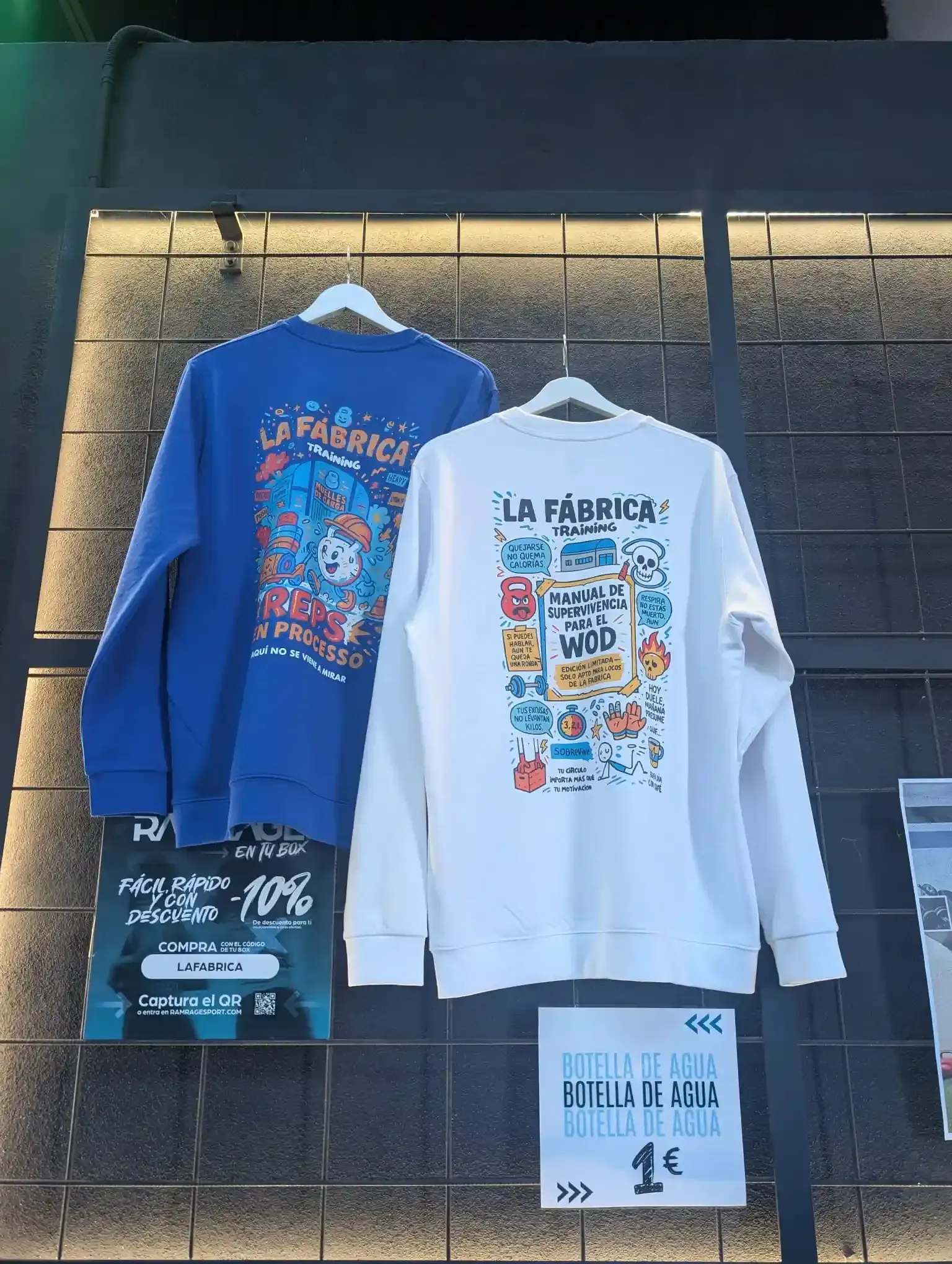 Dos sudaderas: azul y blanca, expuestas. La sudadera azul tiene un diseño de dibujos animados; la blanca dice 