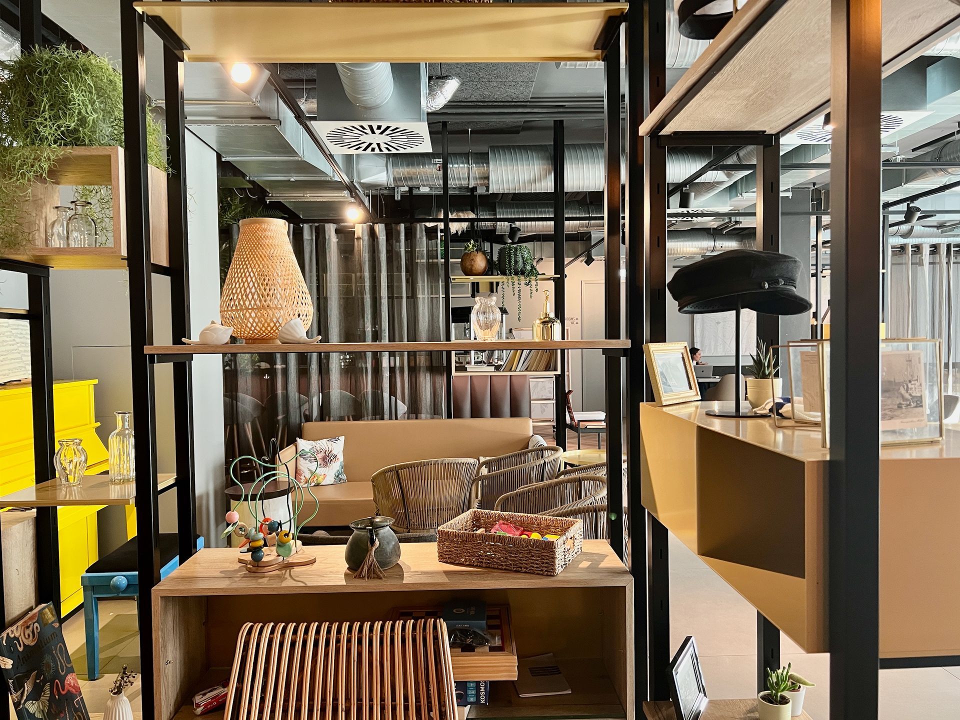 Ein moderner Verkaufsraum mit dekorierten Regalen, einer gewebten Lampe und einer Hutauslage, in dessen Nähe ein gelbes Klavier steht.