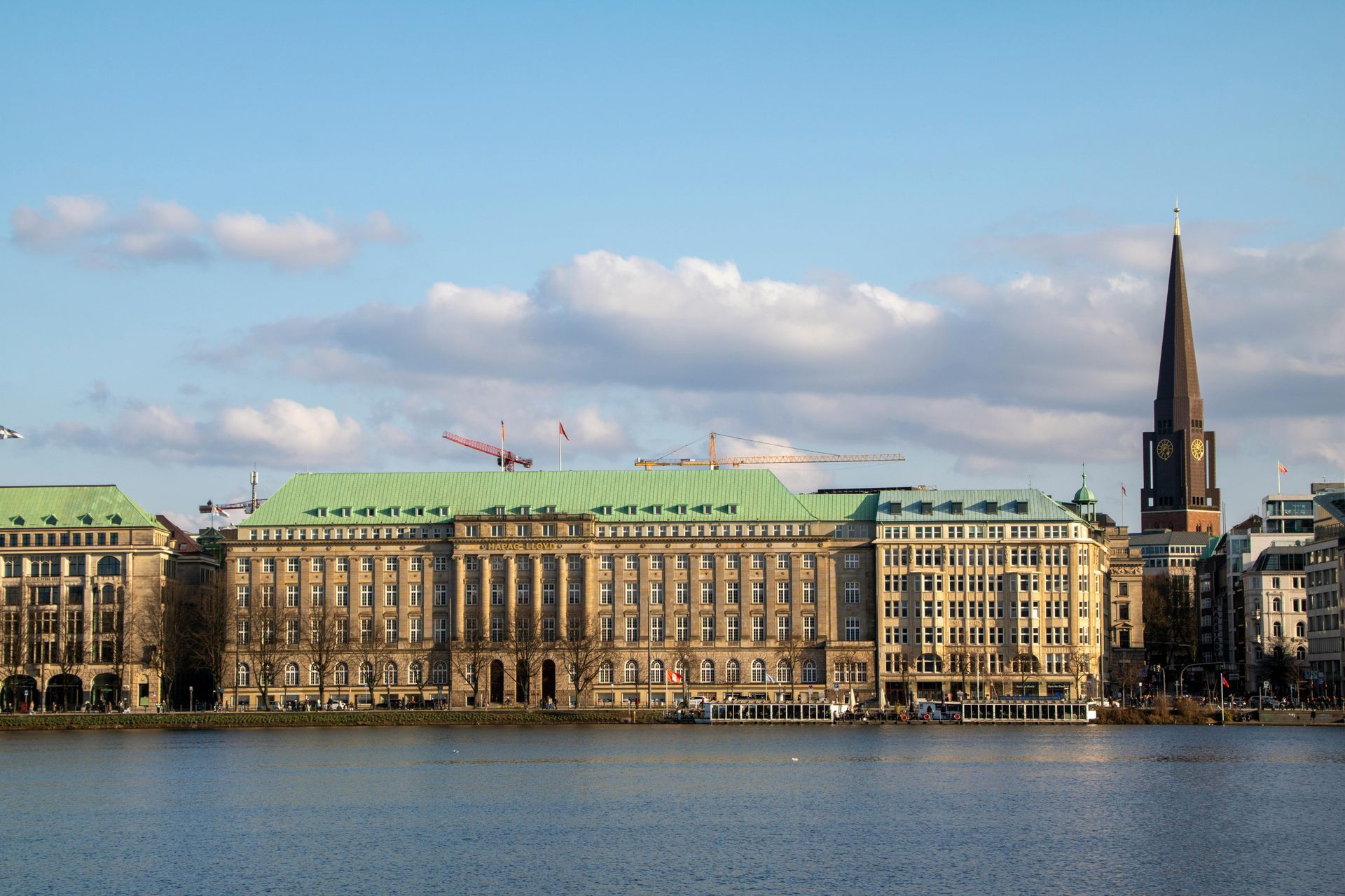 Die Uferpromenade von Hamburg, Deutschland, mit einem markanten Gebäude mit Gründach und einem hohen Kirchturm.