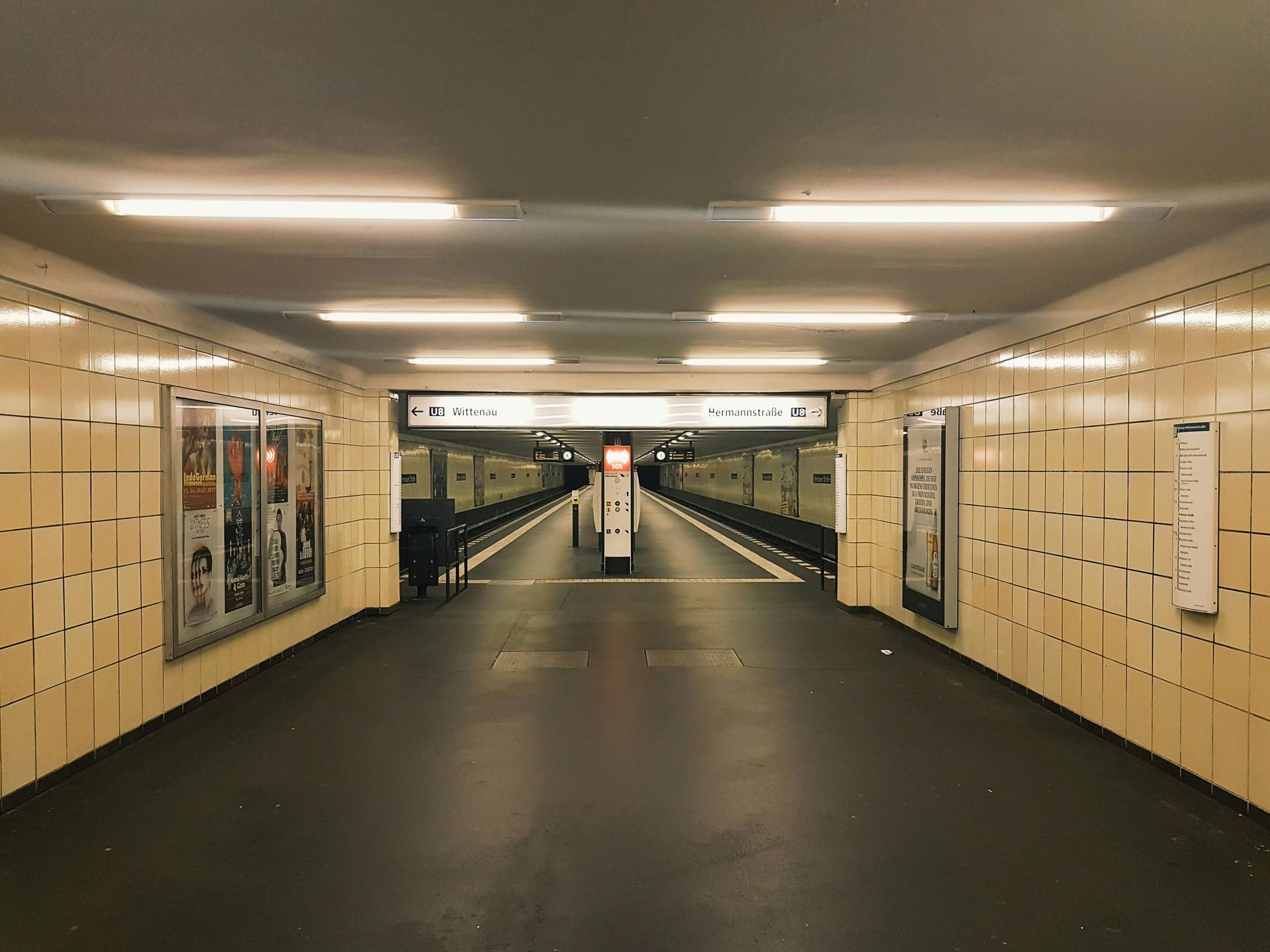 Eine leere unterirdische Fußgängerzone mit beigefarbenen Fliesenwänden, die von Neonröhren an der Decke beleuchtet wird.