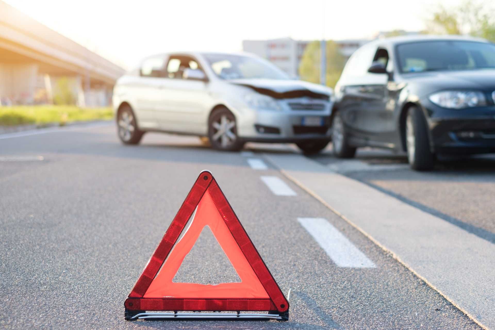 ein rotes Dreieck auf der Straße neben zwei Autos