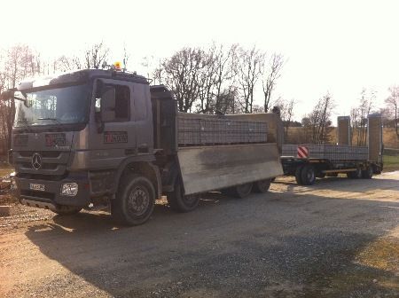 Ein Muldenkipper mit Anhänger steht am Straßenrand.