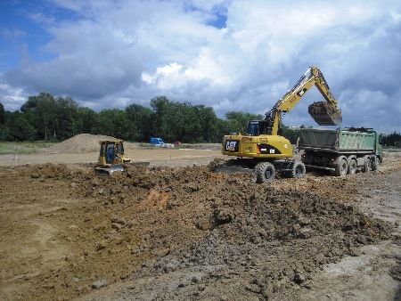 Ein Cat-Bagger lädt Erde in einen Muldenkipper.