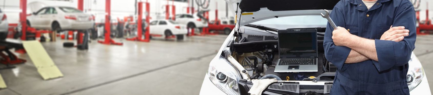 Un mécanicien inspecte une voiture au capot ouvert dans un garage automobile lumineux.