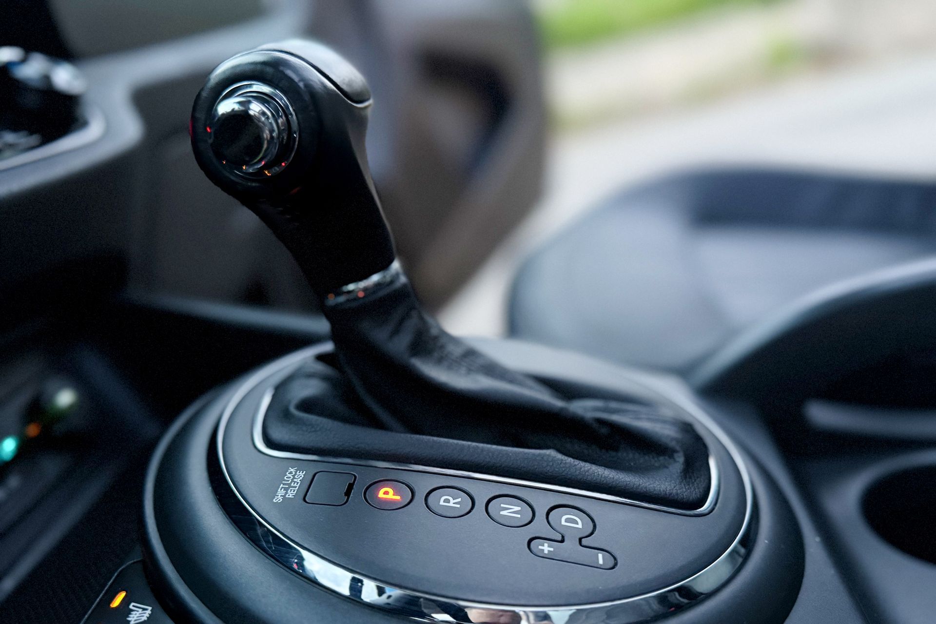 Gros plan sur le levier de vitesses automatique d’une voiture et les boutons de la console centrale, dans un habitacle sombre.