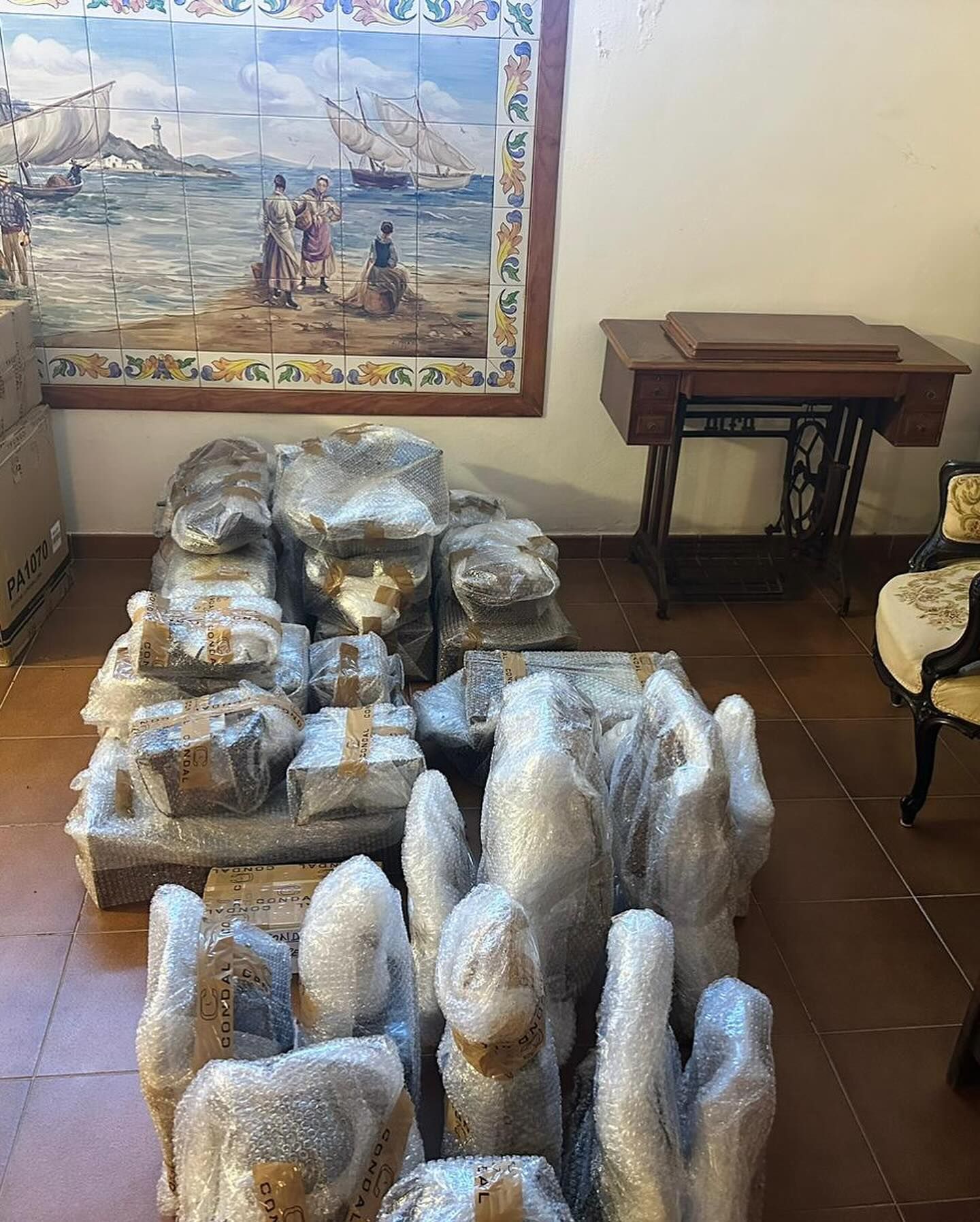 Una habitación con muchas esculturas envueltas en plástico y una pintura en la pared.