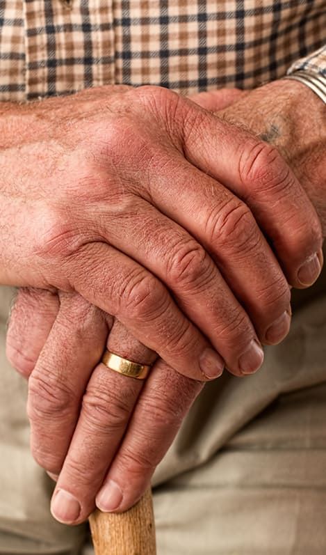 Mains d'un homme âgé appuyées sur une canne en bois