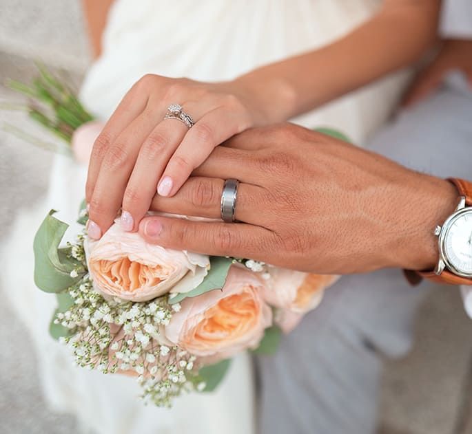 Jeunes mariés, main gauche posée sur un bouquet de fleurs