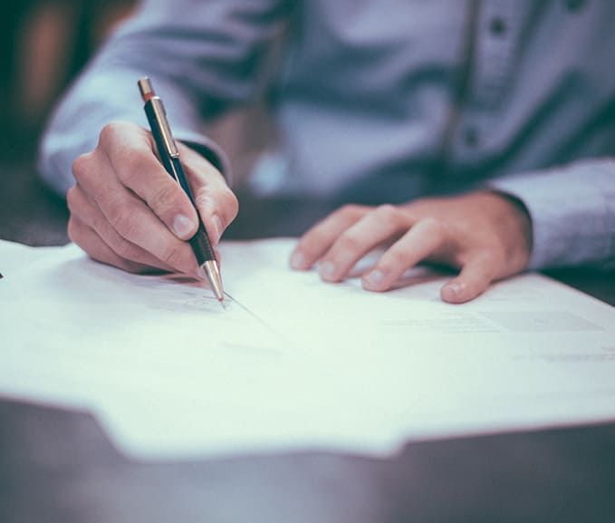 Personne assise à un bureau qui signe des documents