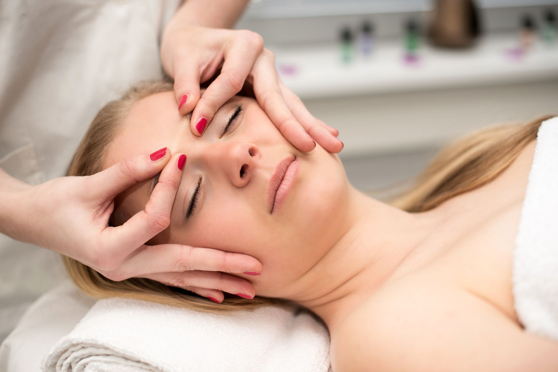 Una mujer está recibiendo un masaje facial en un spa.