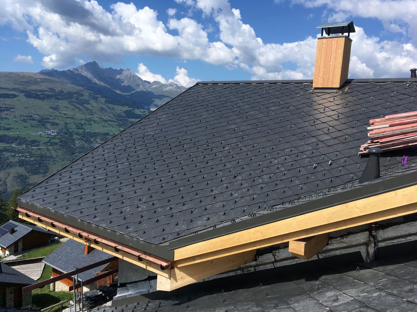 Toit d'ardoise sur un chalet avec des montagnes et des nuages ​​en arrière-plan