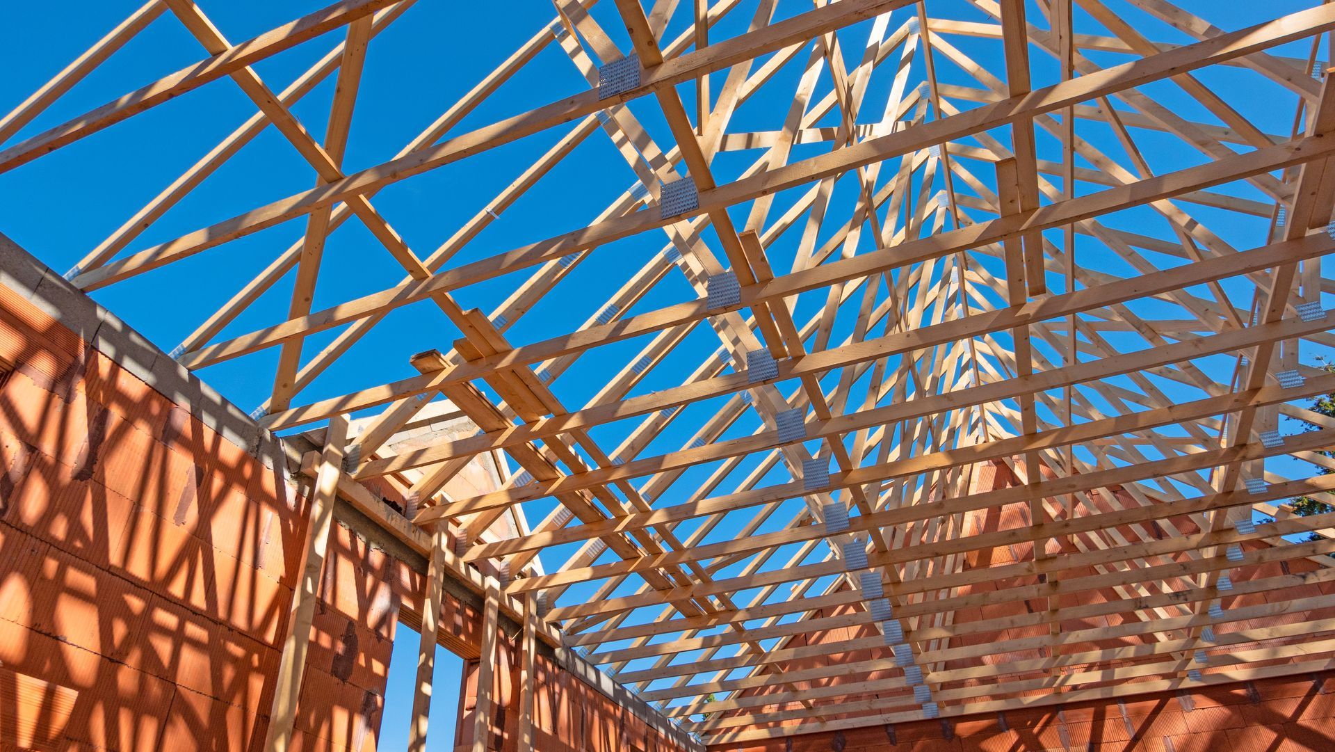 Bâtiment à ossature bois en construction, charpente apparente sur fond de ciel bleu