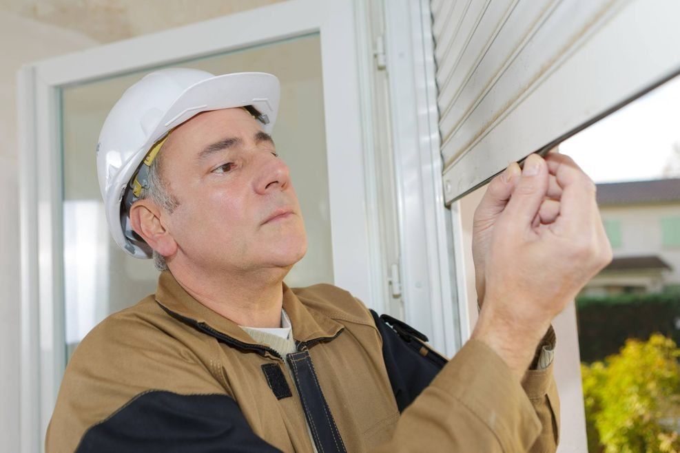 Un hombre está instalando una persiana en una ventana.