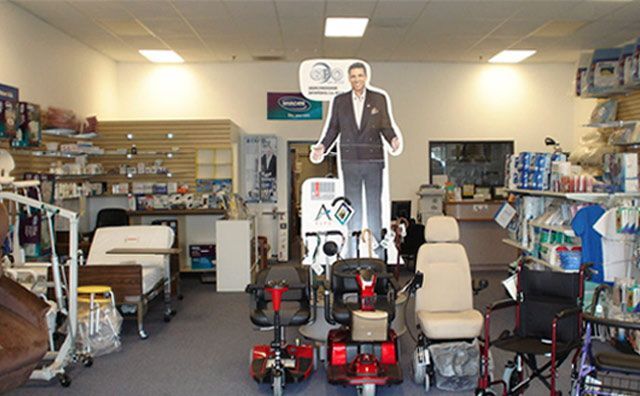 Un hombre con traje está de pie junto a un scooter en una tienda.