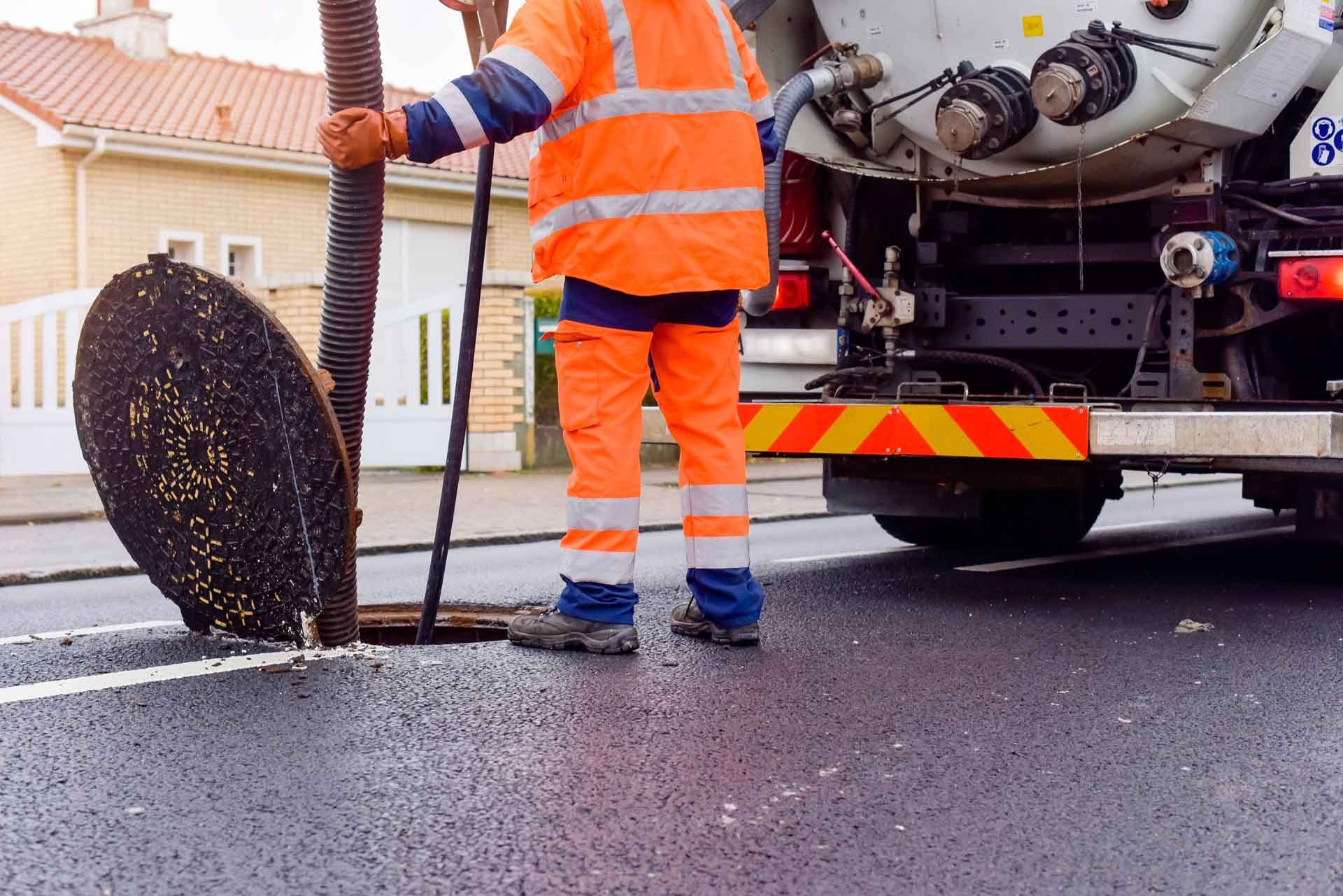 Intervention d'un vidangeur dans une bouche de canalisation à l'aide d'un camion