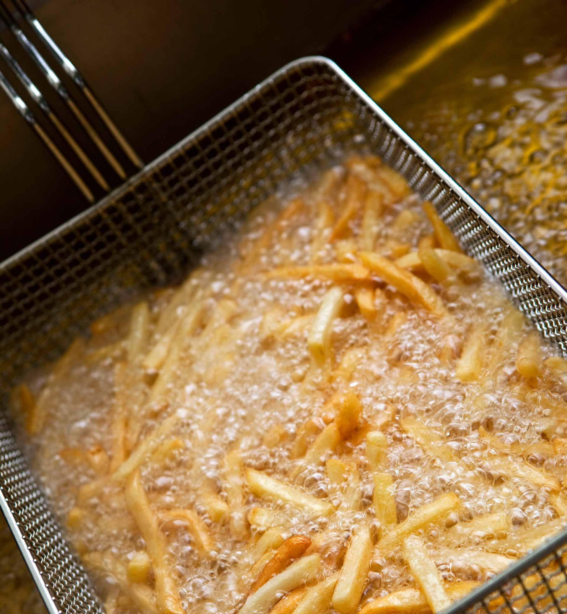 Une friteuse vue de haut dans un bac à graisses en ébullition