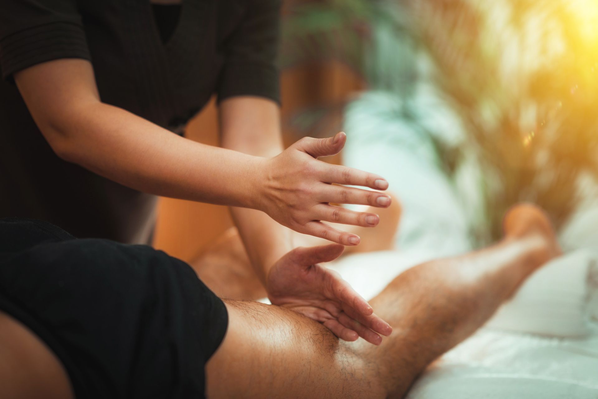Masajista realizando un masaje de piernas; manos con movimientos de amasado sobre una pierna, en interiores.