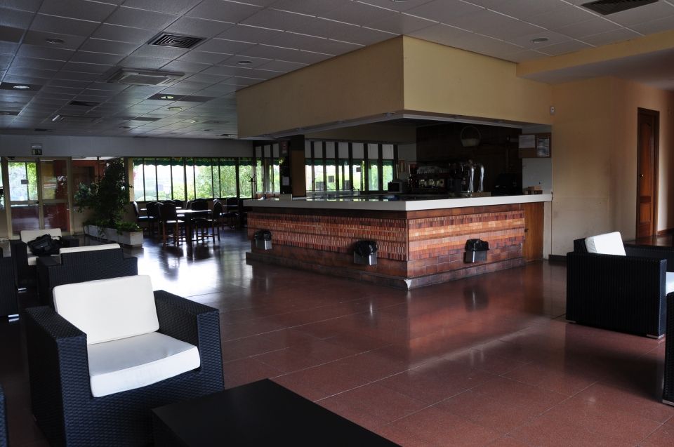 Vista interior de una sala de espera con barra, asientos y ventanas