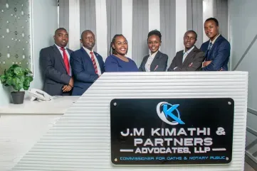 A group of people standing in front of a sign that says j.m kimathi & partners advocates llp.