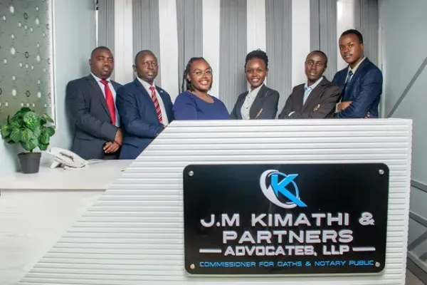A group of people standing in front of a sign that says j.m kimathi & partners advocates llp.