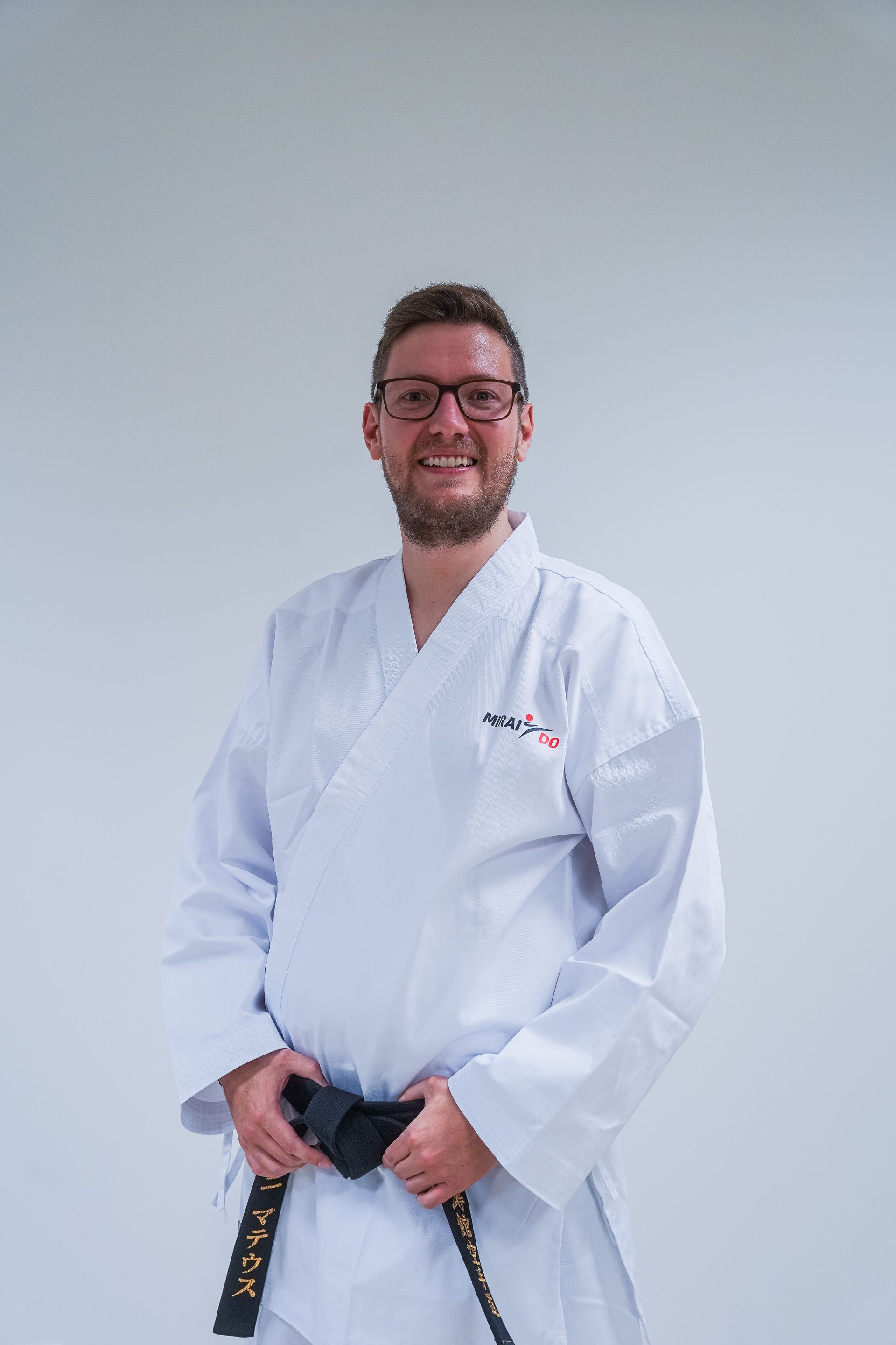 Karatekämpfer in Haltung, graue Silhouette, weißer Gi, bereit zum Schlag.