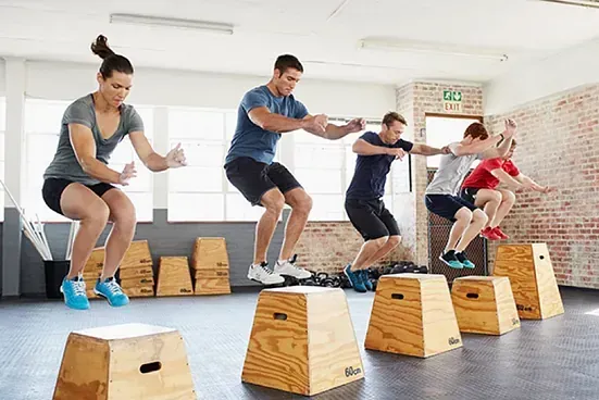 Un grupo de personas está saltando bloques de madera en un gimnasio.