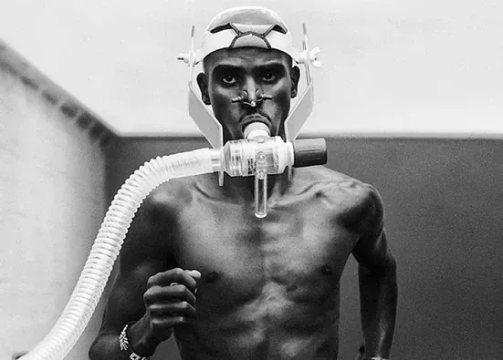 Una fotografía en blanco y negro de un hombre sin camisa que lleva una máscara de oxígeno.