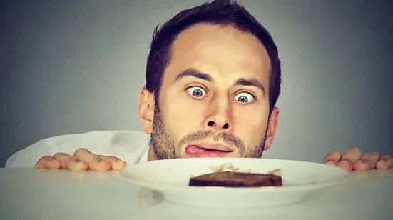 Un hombre saca la lengua a un plato de comida.