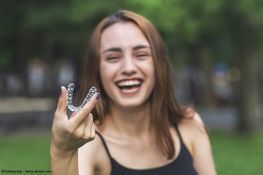 Zahnarztpraxis Matthias Richter Eine Frau lächelt und hält eine Knirschschiene hoch