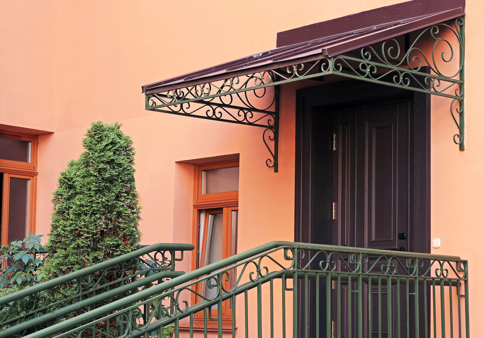 Porte d'entrée avec auvent et balustrade en fer forgé vert