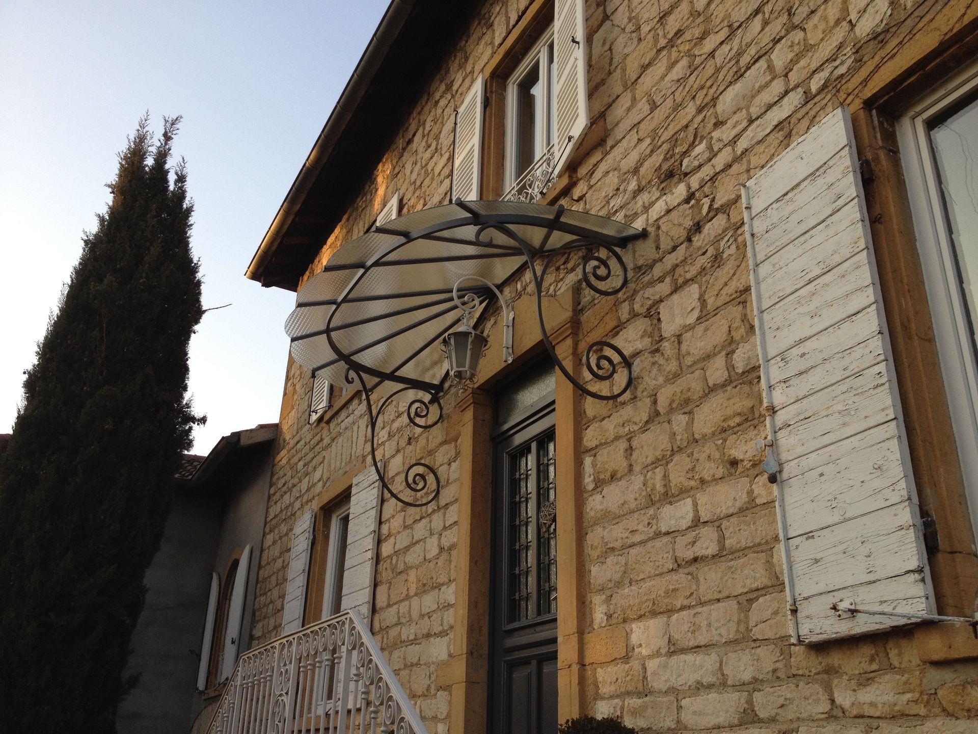 Entrée d'un bâtiment en pierre avec une marquise en fer forgé