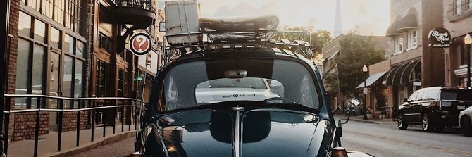 Schwarzer VW-Käfer mit Gepäckträger in einer Kleinstadt