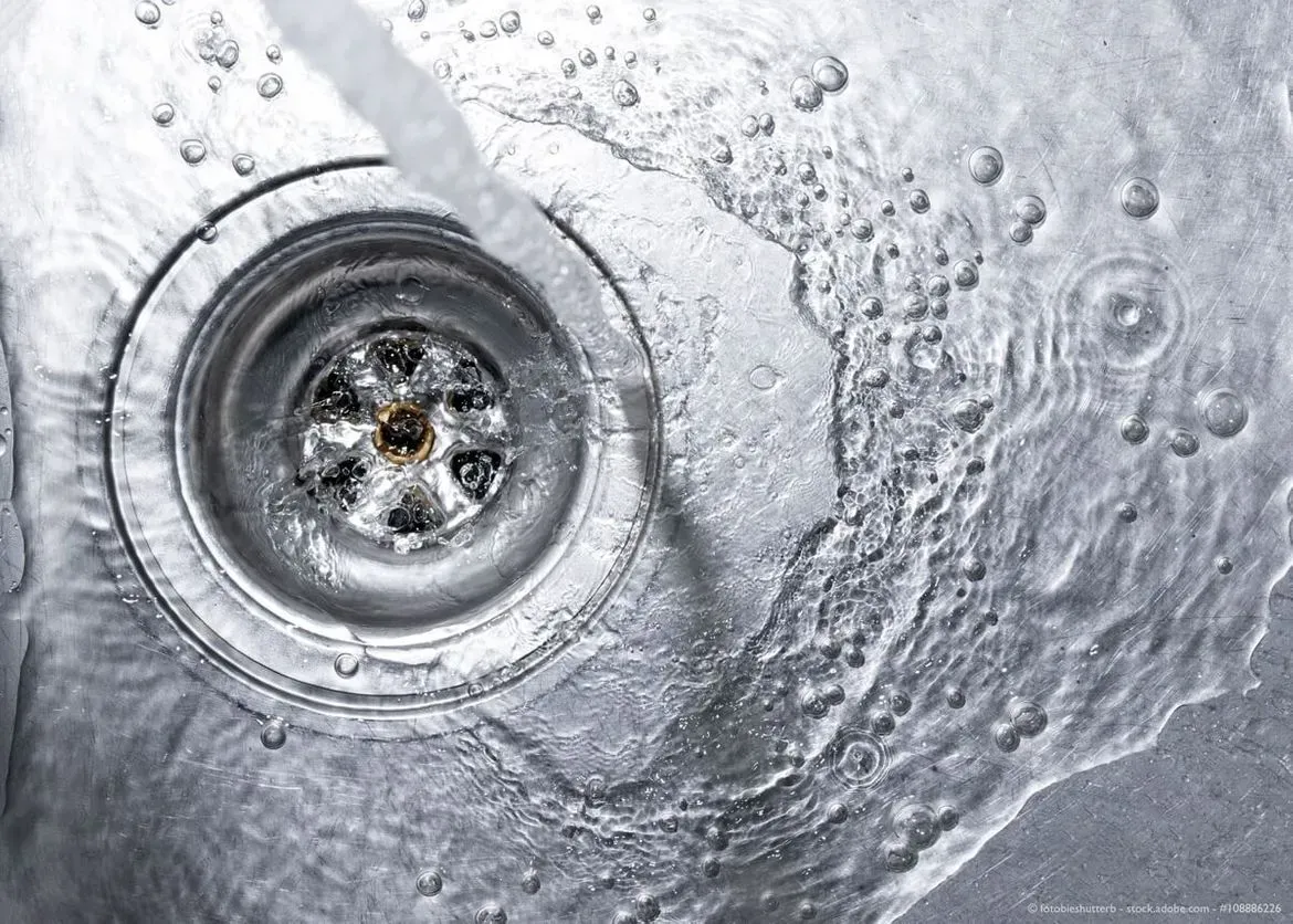 Eine Nahaufnahme eines Spülbeckenabflusses, aus dem Wasser läuft.