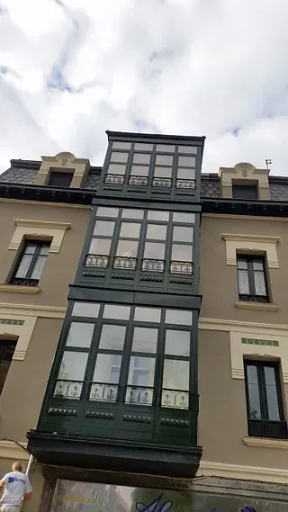 Un edificio alto con muchas ventanas y un balcón.