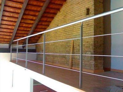 Un balcón con barandilla y una pared de ladrillo al fondo.