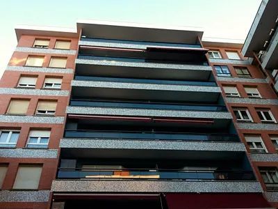 Mirando hacia arriba a un gran edificio de apartamentos con muchos balcones.