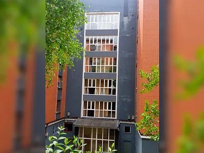 Un gran edificio con muchas ventanas está rodeado de árboles.