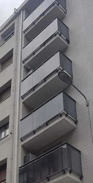 Un edificio con muchos balcones y una farola a un costado.