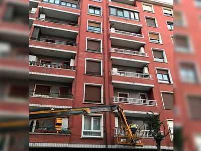 Un gran edificio de ladrillo rojo con una grúa delante.