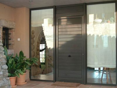 Una puerta con muchas ventanas y plantas en macetas delante de ella.