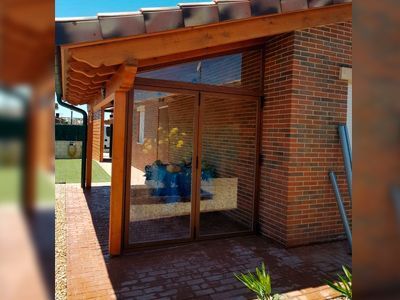 Un edificio de ladrillo con un porche de madera y puertas corredizas de vidrio.