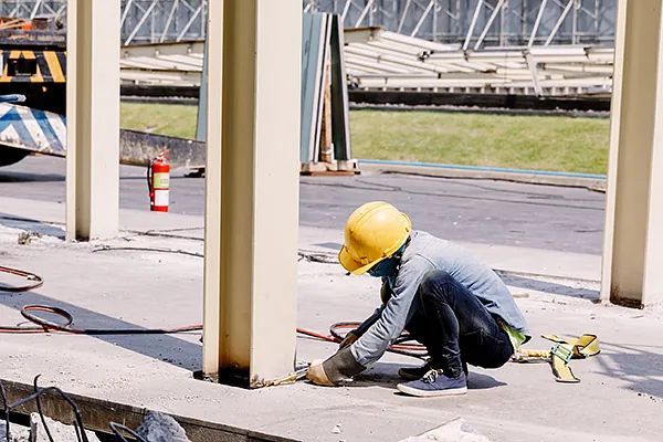 Un trabajador de la construcción que lleva un casco está arrodillado en el suelo.