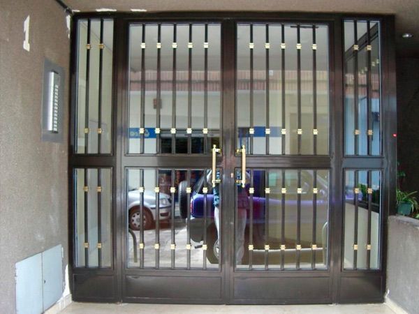 Una entrada vallada a un edificio con un coche aparcado delante.