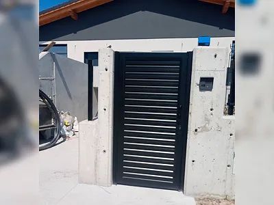 Una puerta negra está delante de una pared de hormigón.