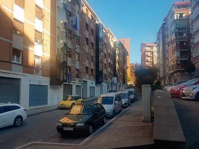 Una fila de coches están estacionados al costado de una calle de la ciudad.
