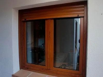 Una ventana de madera con una contraventana está en una pared blanca.