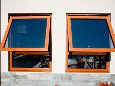 Dos ventanas de madera se abren a un edificio blanco.