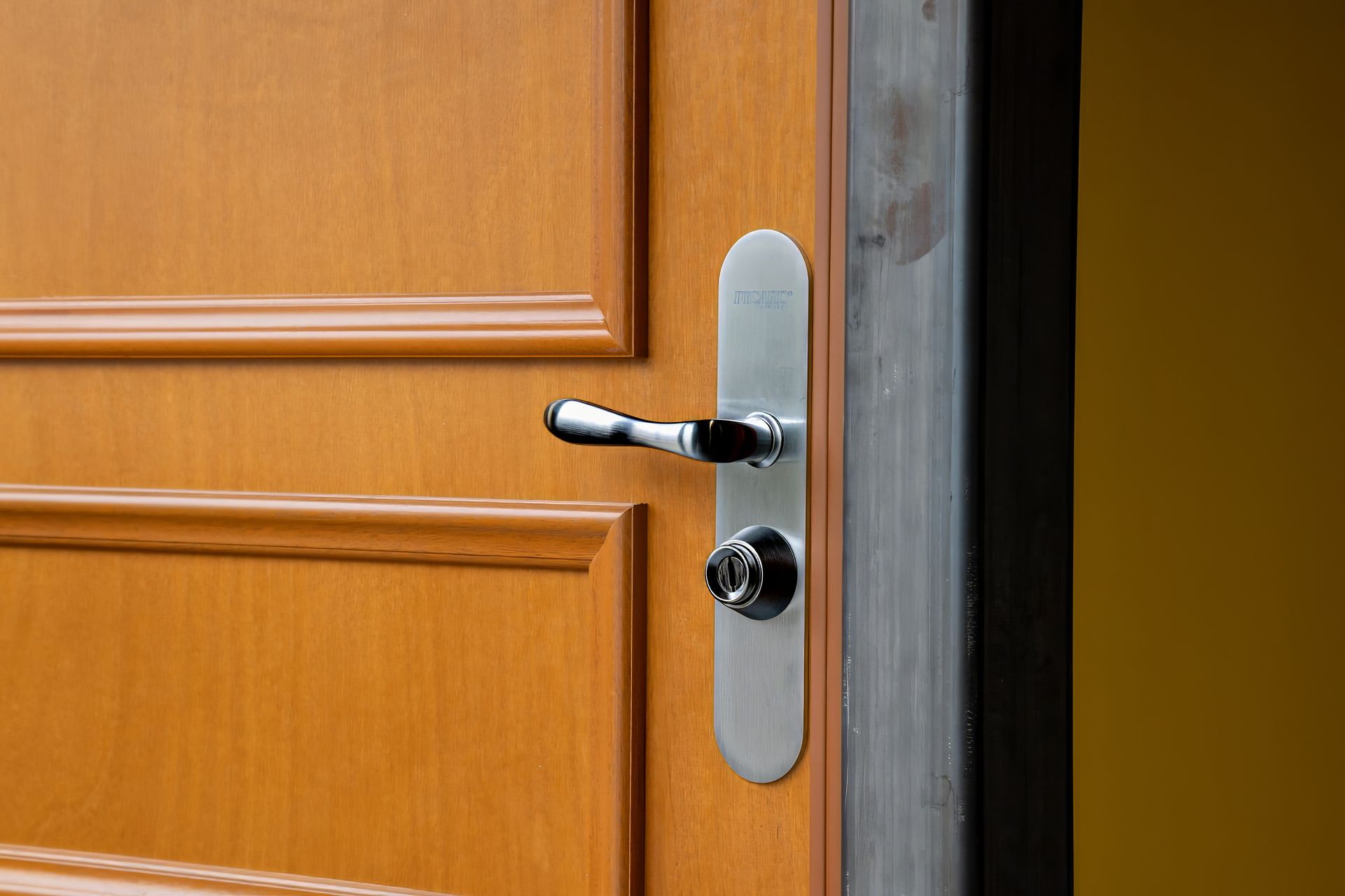Porte en bois avec poignée et serrure argentées, partiellement ouverte.