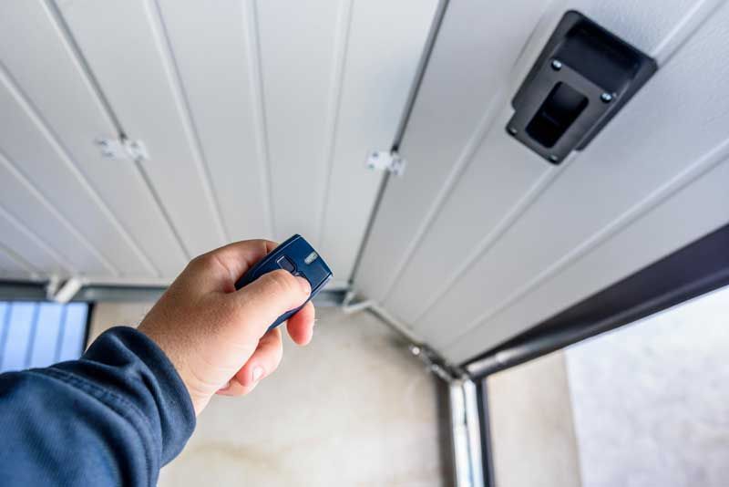 Porte de garage blanche en train d'être ouverte avec télécommande