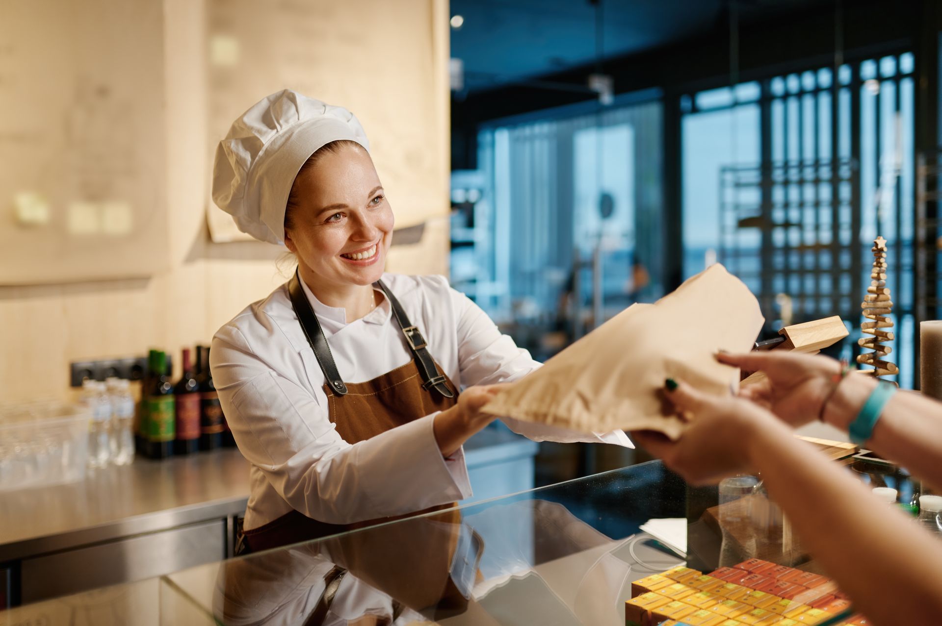 Un chef sonriente en un restaurante entrega un alimento envuelto a un cliente.